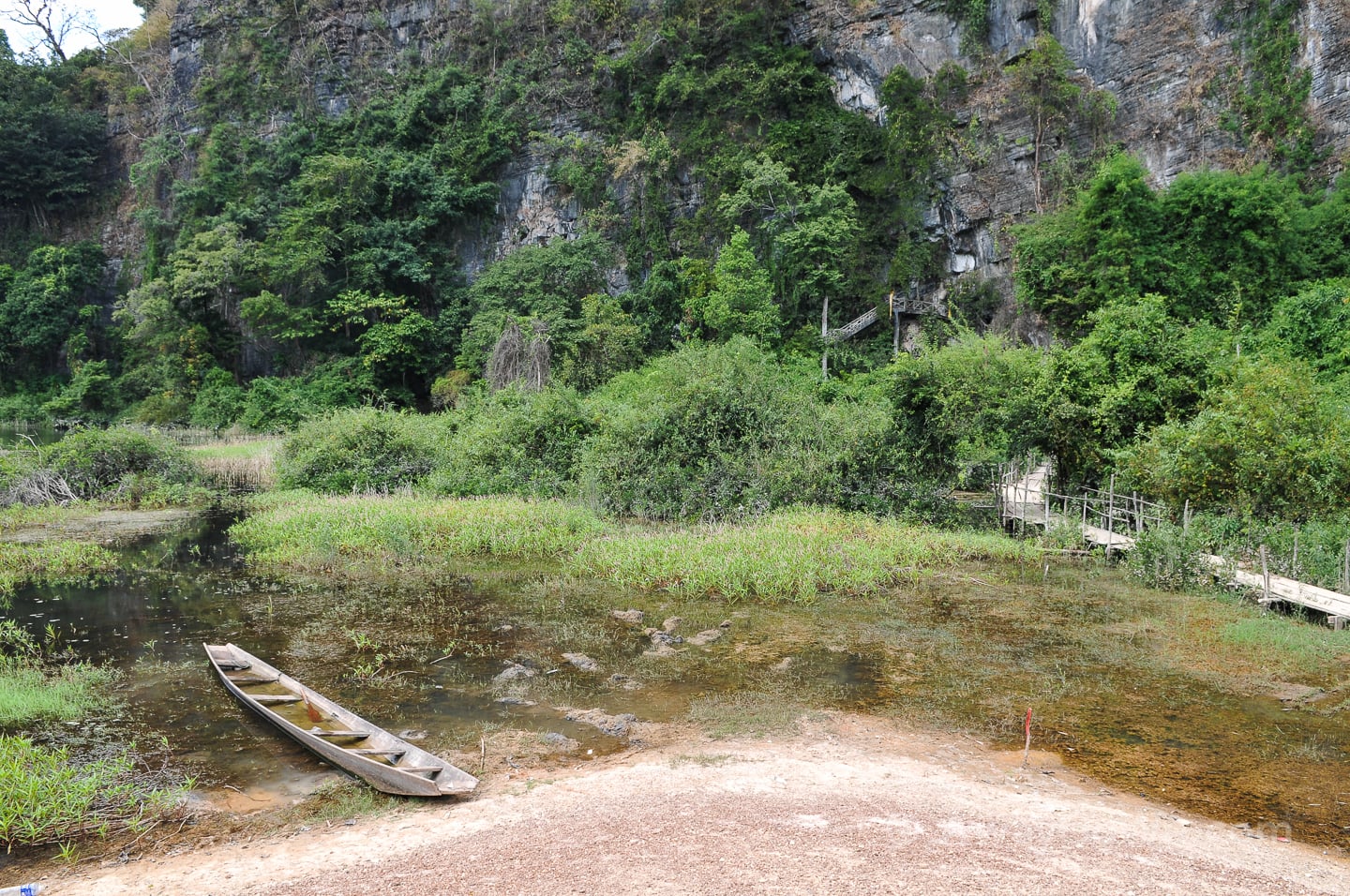 wooden boat in pond near buddha cave along the thakhek loop route