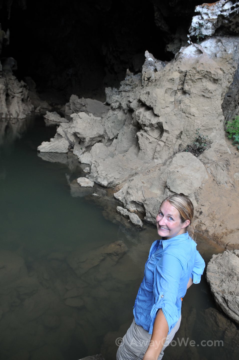 woman standing near water-filled cave in laos
