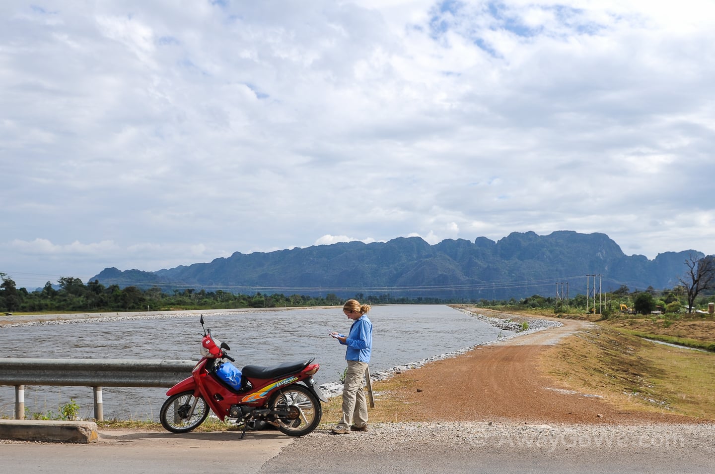 standing near motorbike on a bridge in laos