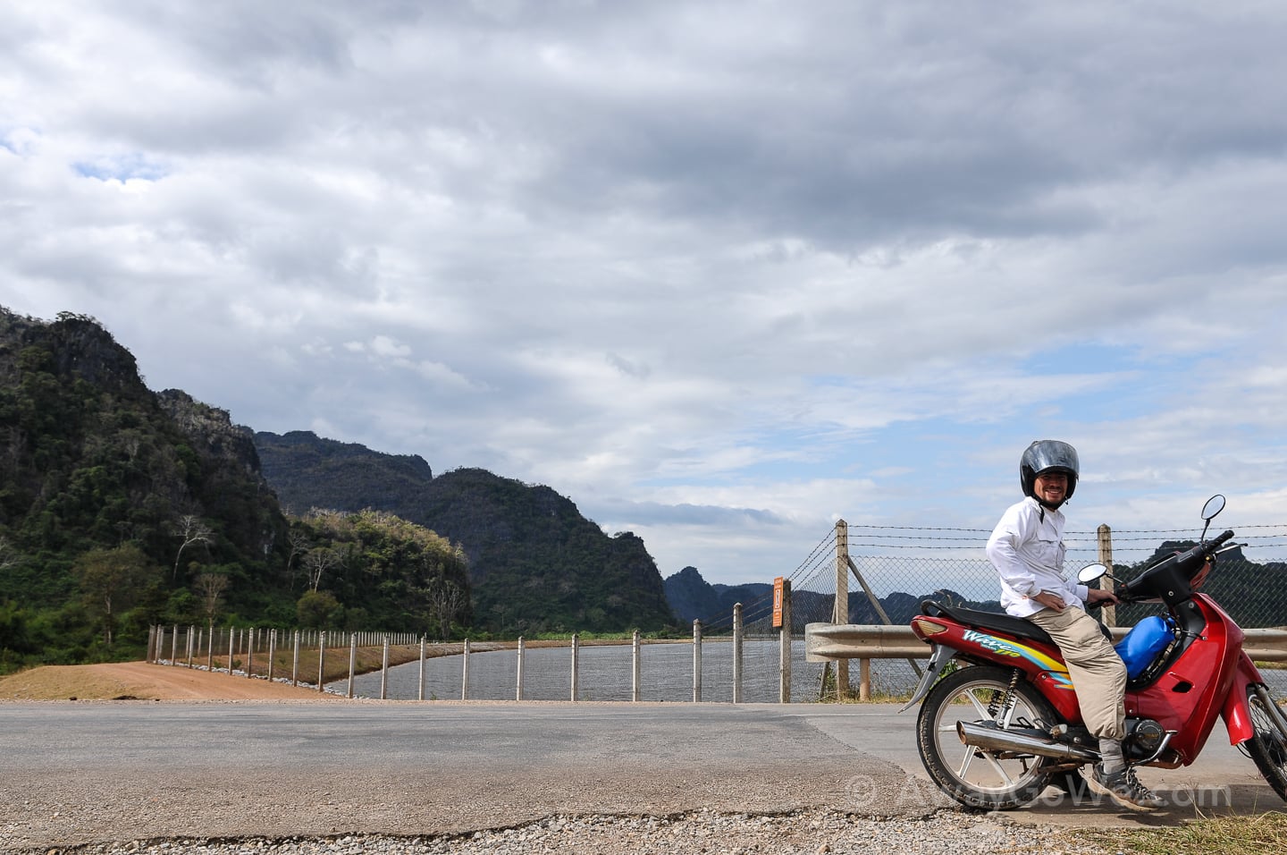 sitting on motorbike near bridge over river in laos